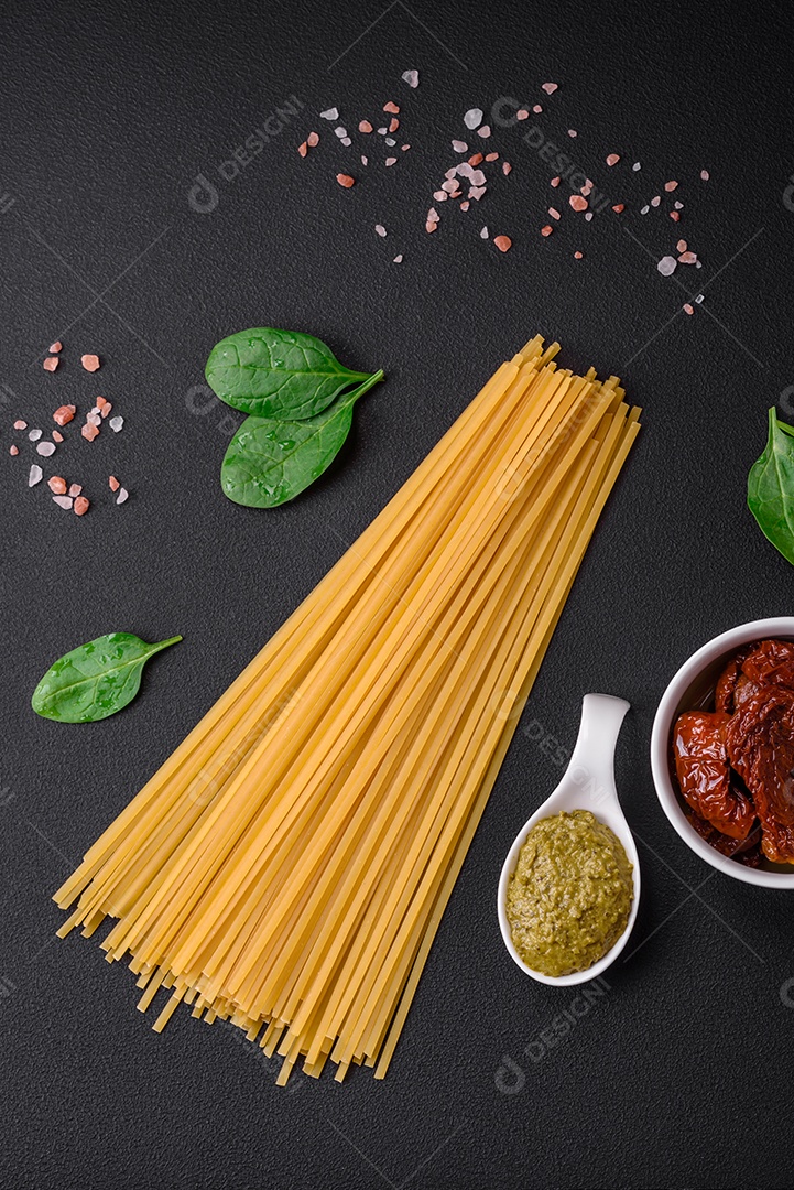Deliciosa massa com espinafre, tomate seco, queijo, cebola, especiarias e ervas sobre um fundo escuro de concreto