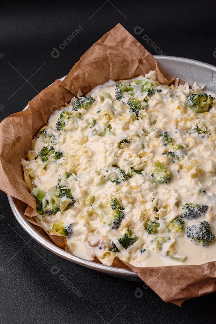 Deliciosa quiche com brócolis, queijo, frango, especiarias e ervas sobre um fundo escuro de concreto