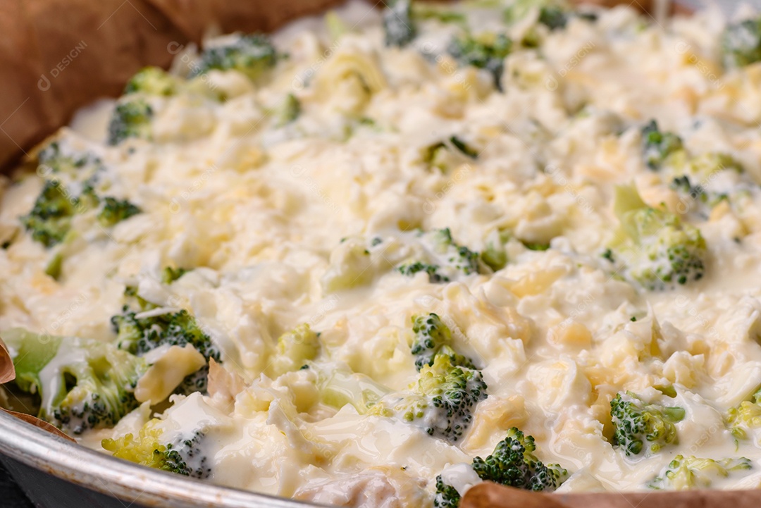 Deliciosa quiche com brócolis, queijo, frango, especiarias e ervas sobre um fundo escuro de concreto