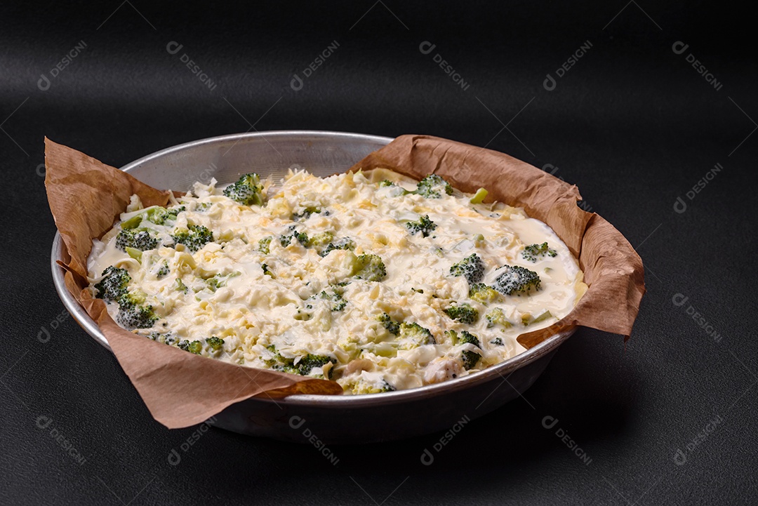 Deliciosa quiche com brócolis, queijo, frango, especiarias e ervas sobre um fundo escuro de concreto