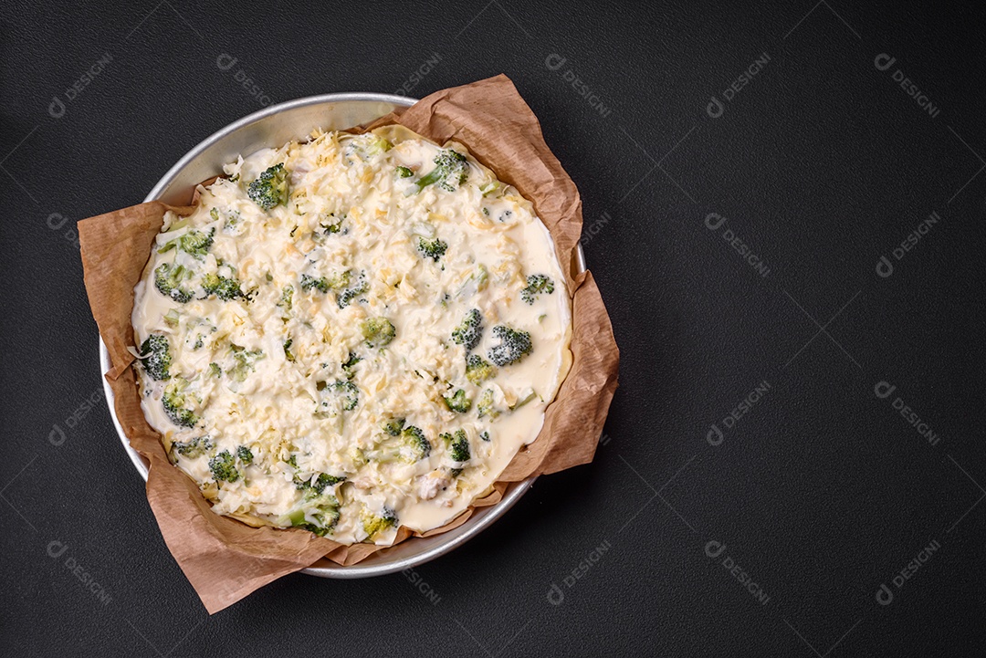 Deliciosa quiche com brócolis, queijo, frango, especiarias e ervas sobre um fundo escuro de concreto