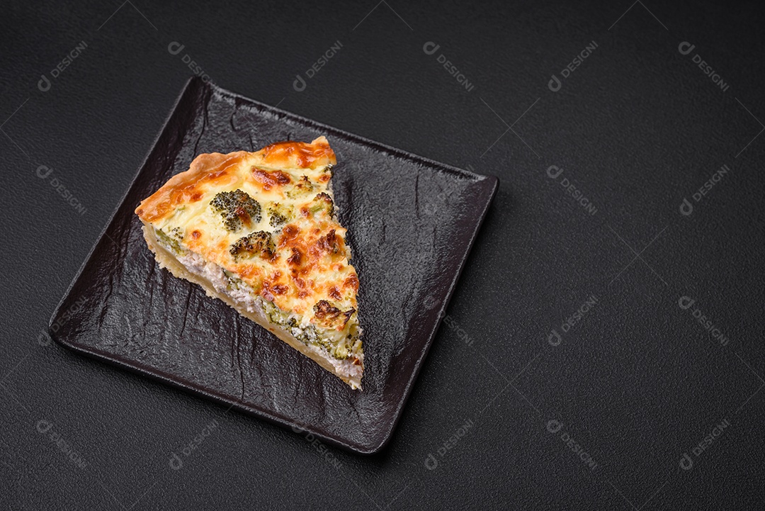 Deliciosa quiche com brócolis, queijo, frango, especiarias e ervas sobre um fundo escuro de concreto