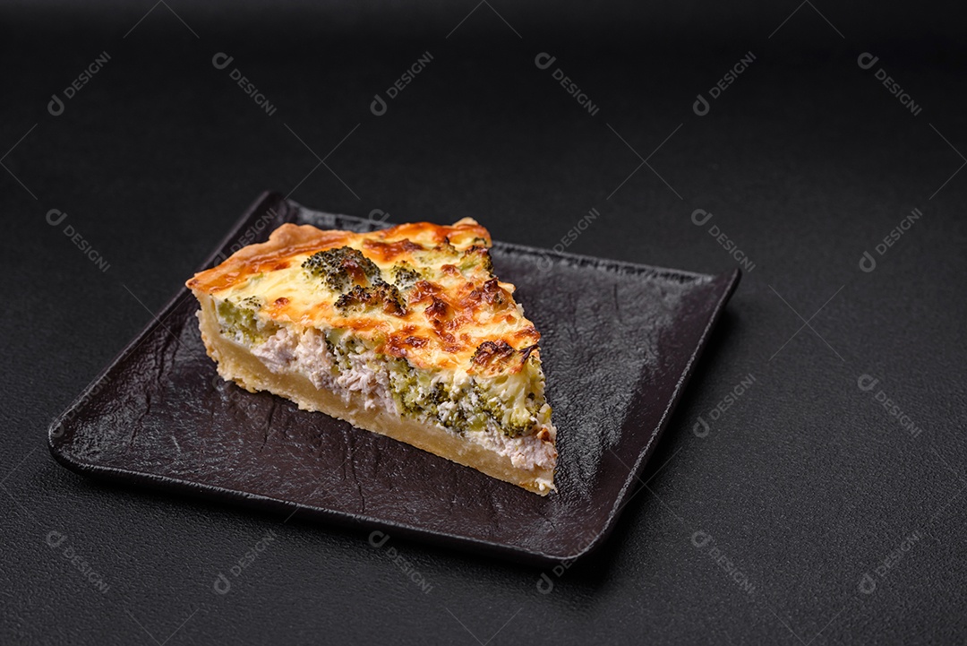 Deliciosa quiche com brócolis, queijo, frango, especiarias e ervas sobre um fundo escuro de concreto