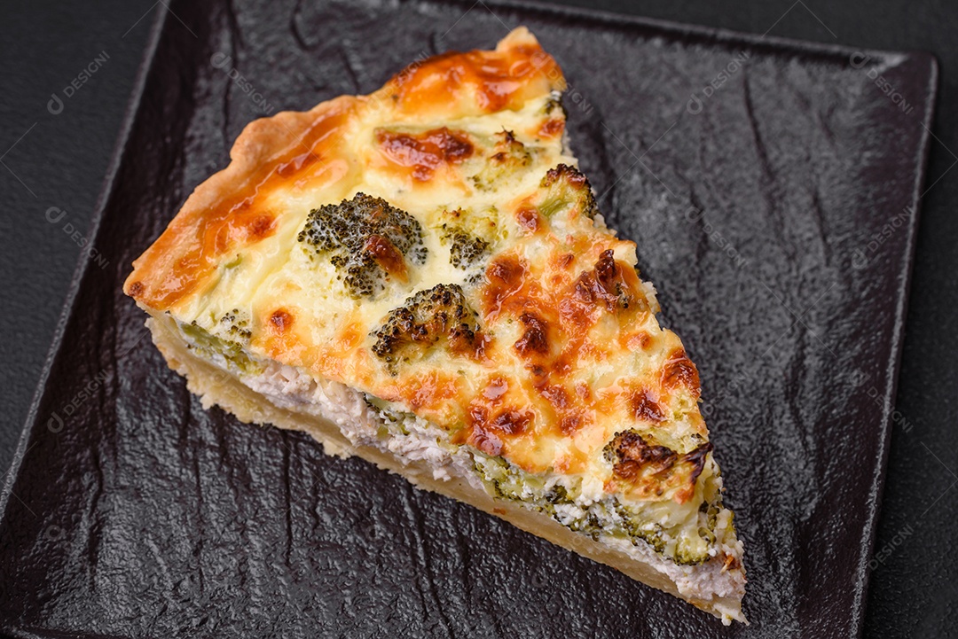 Deliciosa quiche com brócolis, queijo, frango, especiarias e ervas sobre um fundo escuro de concreto