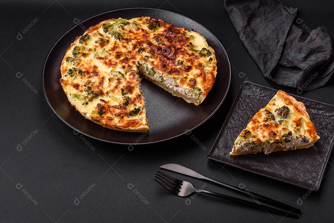 Deliciosa quiche com brócolis, queijo, frango, especiarias e ervas sobre um fundo escuro de concreto