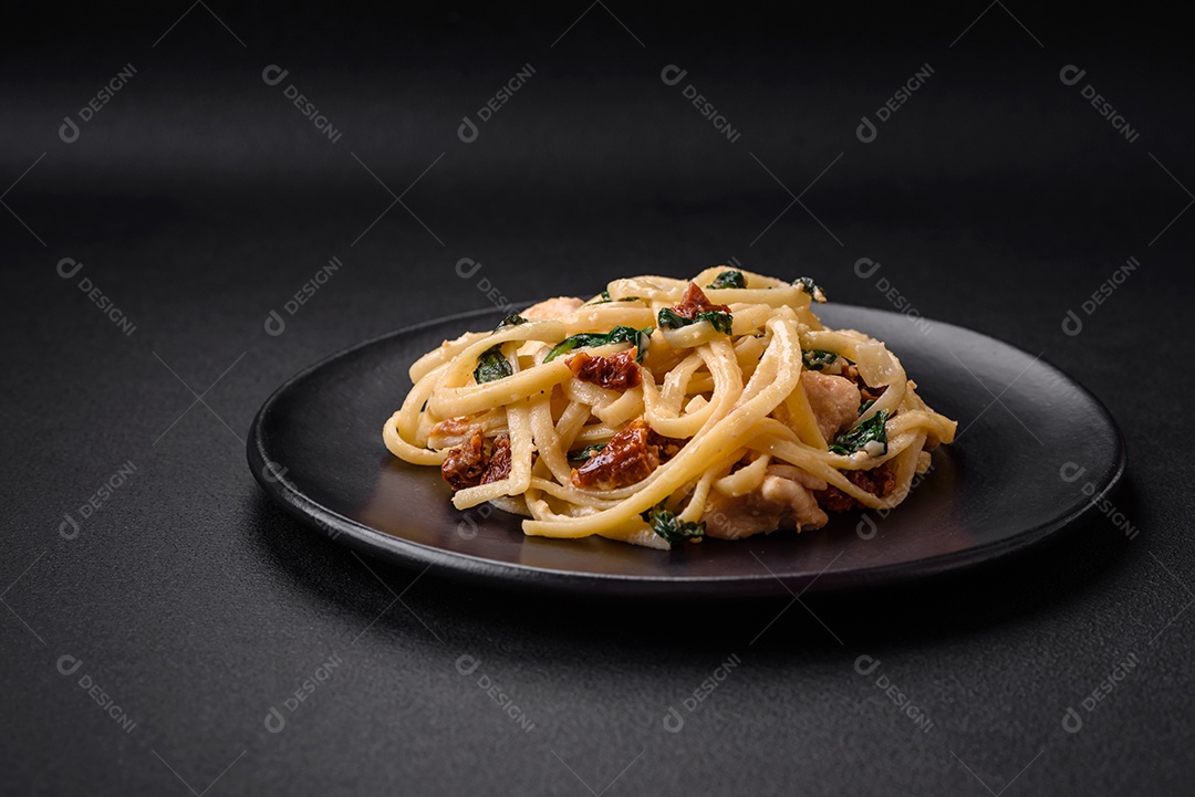 Deliciosa massa com espinafre, tomate seco, queijo, cebola, especiarias e ervas sobre um fundo escuro de concreto
