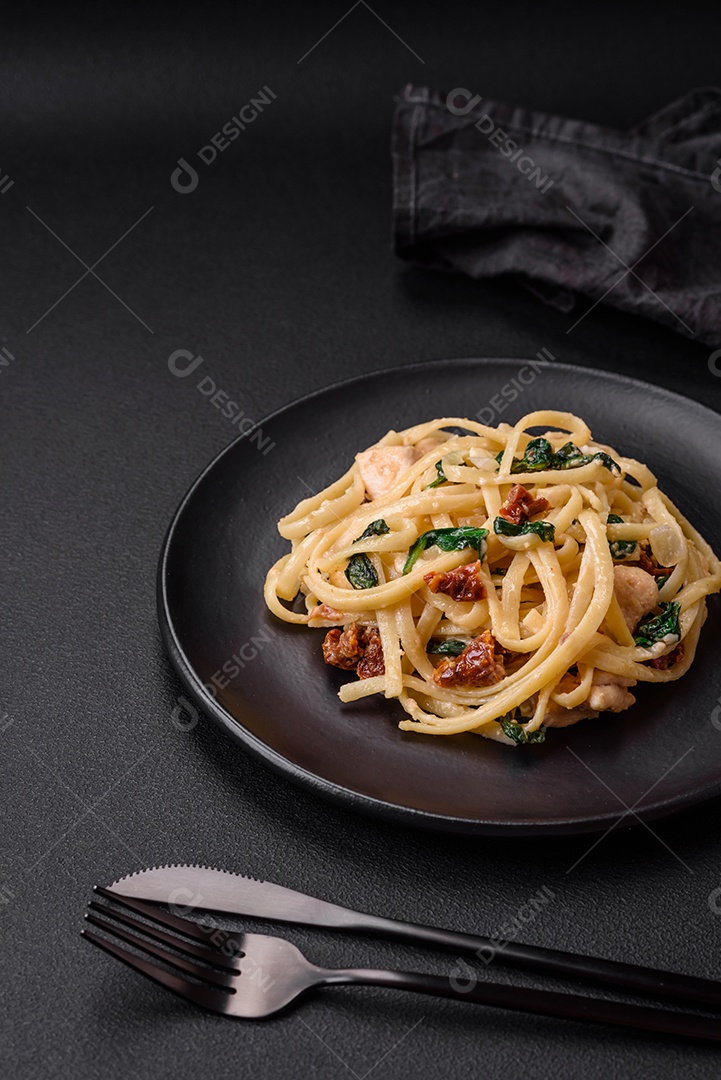 Deliciosa massa com espinafre, tomate seco, queijo, cebola, especiarias e ervas sobre um fundo escuro de concreto