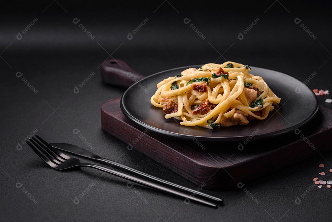 Deliciosa massa com espinafre, tomate seco, queijo, cebola, especiarias e ervas sobre um fundo escuro de concreto