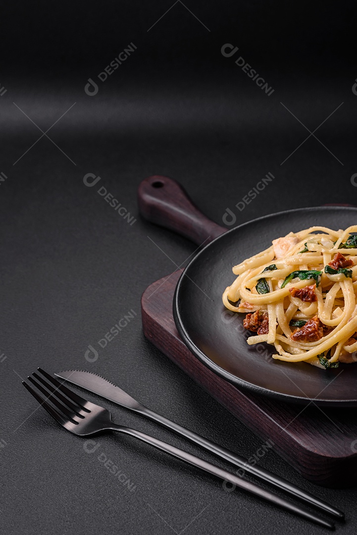 Deliciosa massa com espinafre, tomate seco, queijo, cebola, especiarias e ervas sobre um fundo escuro de concreto