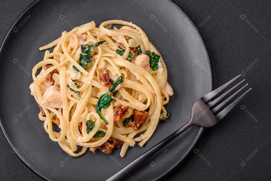 Deliciosa massa com espinafre, tomate seco, queijo, cebola, especiarias e ervas sobre um fundo escuro de concreto