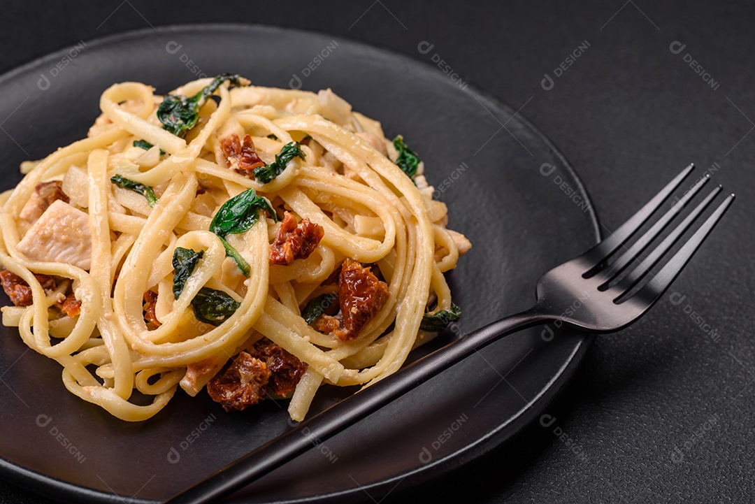 Deliciosa massa com espinafre, tomate seco, queijo, cebola, especiarias e ervas sobre um fundo escuro de concreto