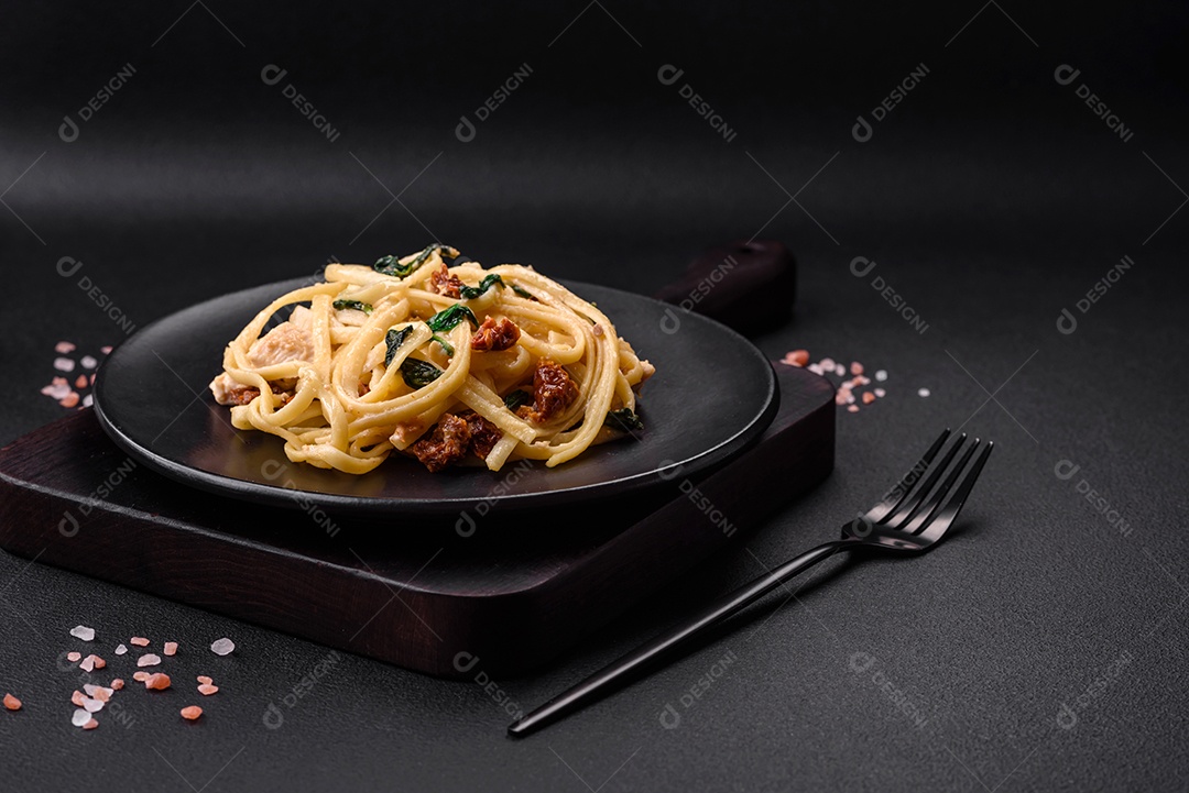 Deliciosa massa com espinafre, tomate seco, queijo, cebola, especiarias e ervas sobre um fundo escuro de concreto
