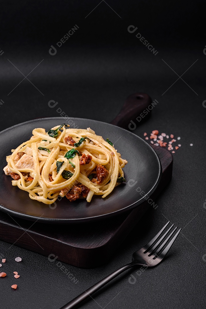 Deliciosa massa com espinafre, tomate seco, queijo, cebola, especiarias e ervas sobre um fundo escuro de concreto