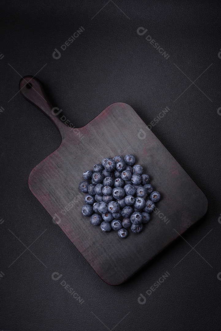 Deliciosos mirtilos frescos em um fundo de concreto preto textural. Colhendo frutas da estação