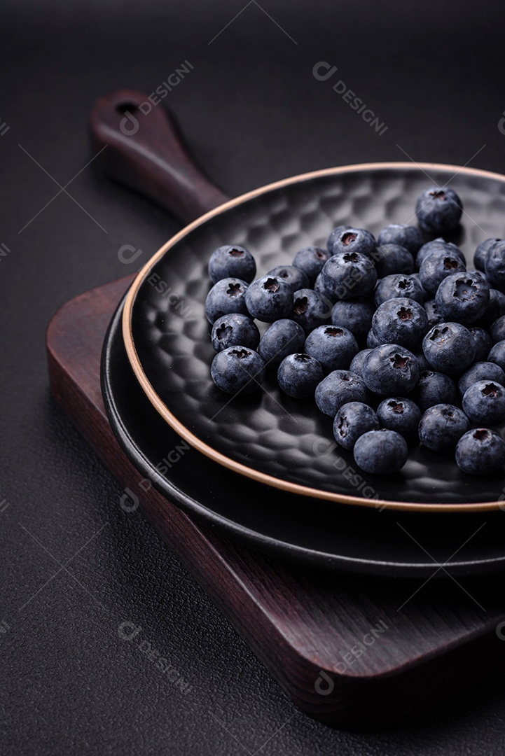 Deliciosos mirtilos frescos em um fundo de concreto preto textural. Colhendo frutas da estação