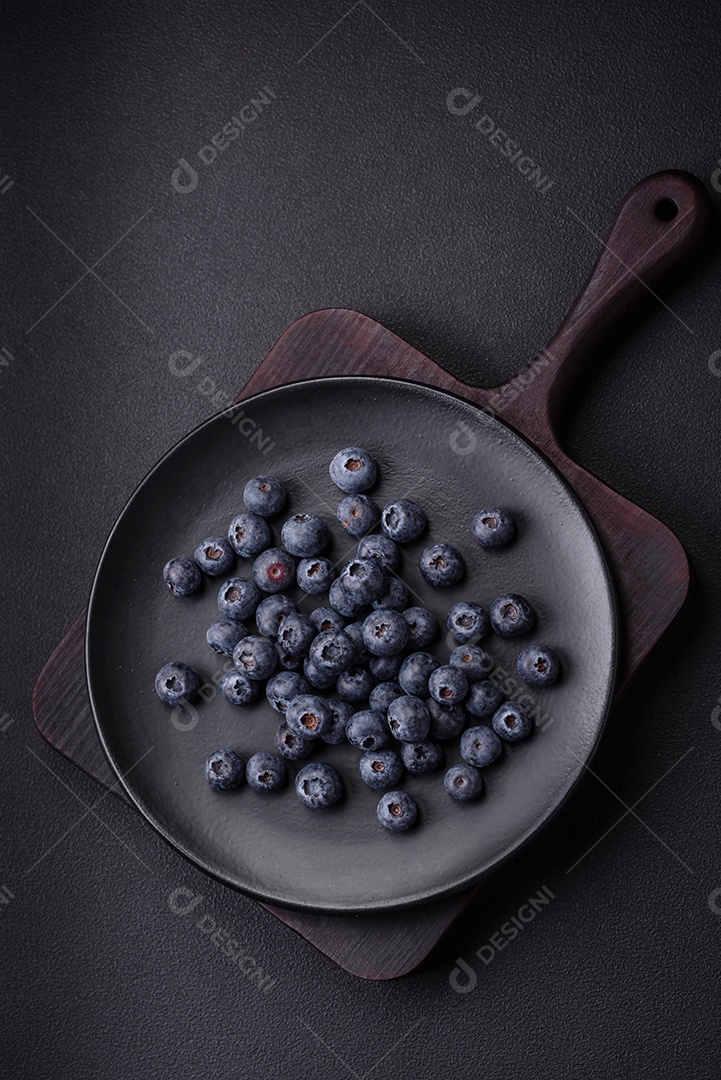 Deliciosos mirtilos frescos em um fundo de concreto preto textural. Colhendo frutas da estação