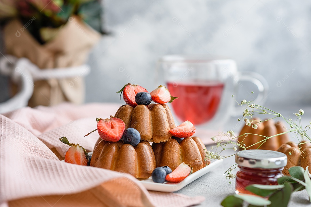 Deliciosos cupcakes ou muffins com passas e nozes, morangos e mirtilos num prato de cerâmica sobre uma mesa de concreto texturizado