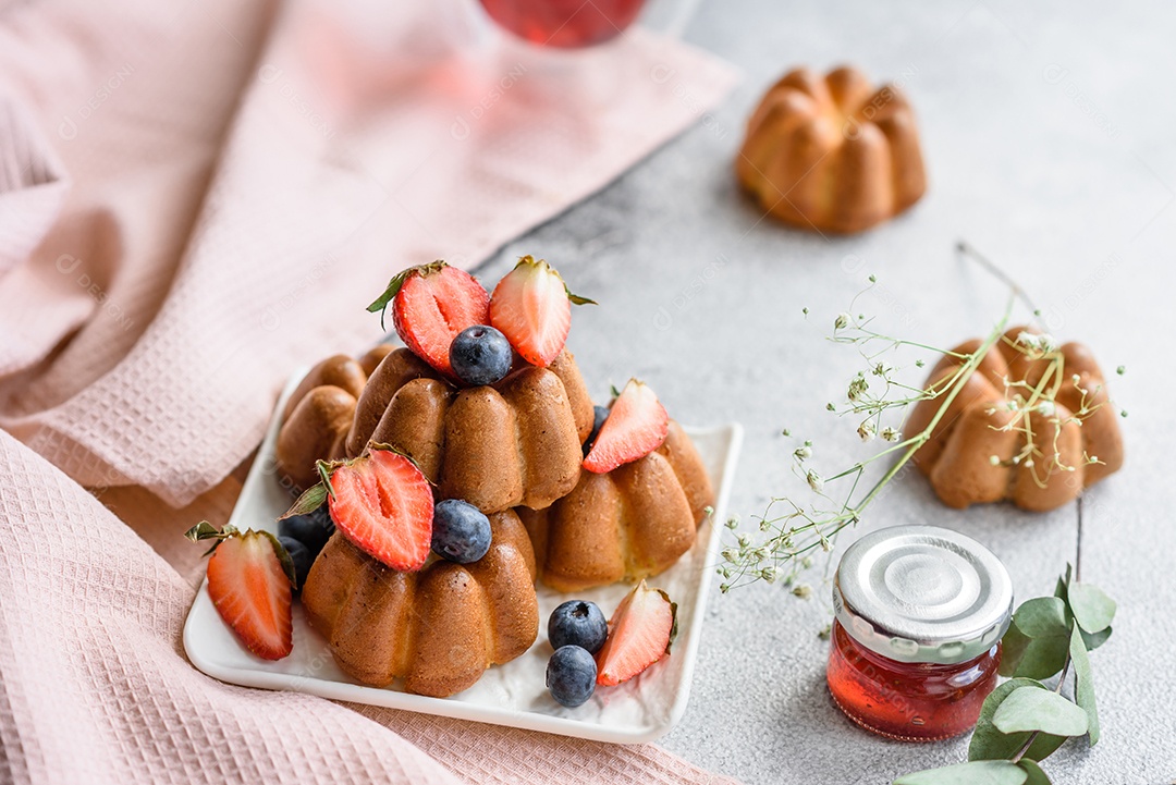 Deliciosos cupcakes ou muffins com passas e nozes, morangos e mirtilos num prato de cerâmica sobre uma mesa de concreto texturizado