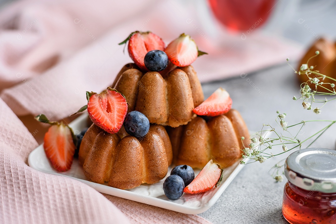 Deliciosos cupcakes ou muffins com passas e nozes, morangos e mirtilos num prato de cerâmica sobre uma mesa de concreto texturizado