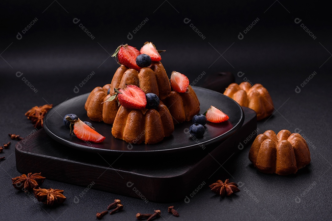 Deliciosos cupcakes ou muffins com passas e nozes, morangos e mirtilos num prato de cerâmica sobre uma mesa de concreto texturizado