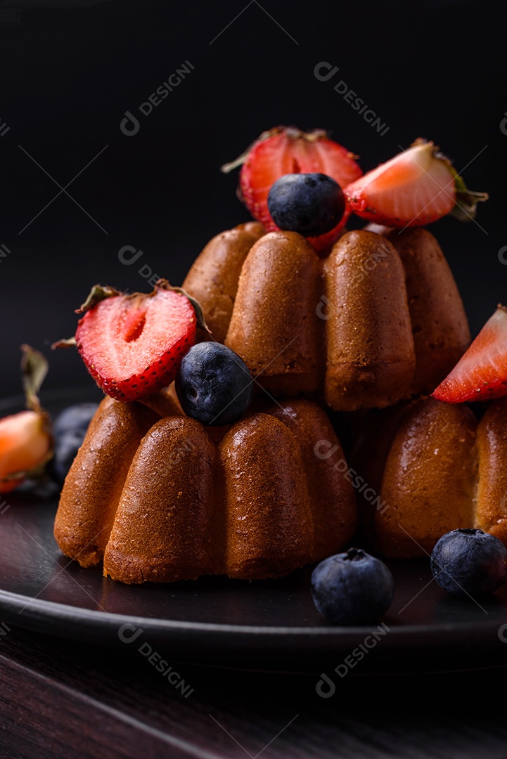 Deliciosos cupcakes ou muffins com passas e nozes, morangos e mirtilos num prato de cerâmica sobre uma mesa de concreto texturizado