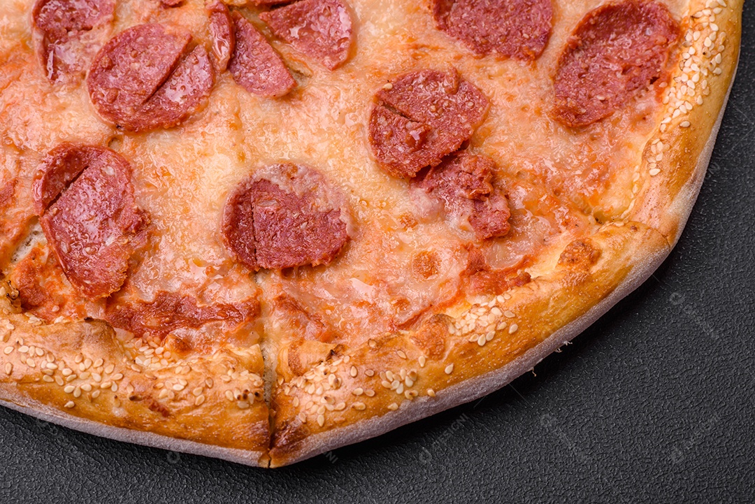 Deliciosa pizza de pepperoni fresca com sementes de gergelim nas laterais sobre um fundo de concreto preto