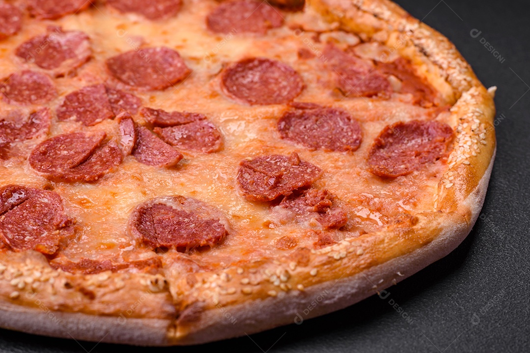 Deliciosa pizza de pepperoni fresca com sementes de gergelim nas laterais sobre um fundo de concreto preto