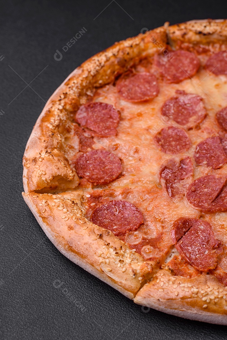 Deliciosa pizza de pepperoni fresca com sementes de gergelim nas laterais sobre um fundo de concreto preto