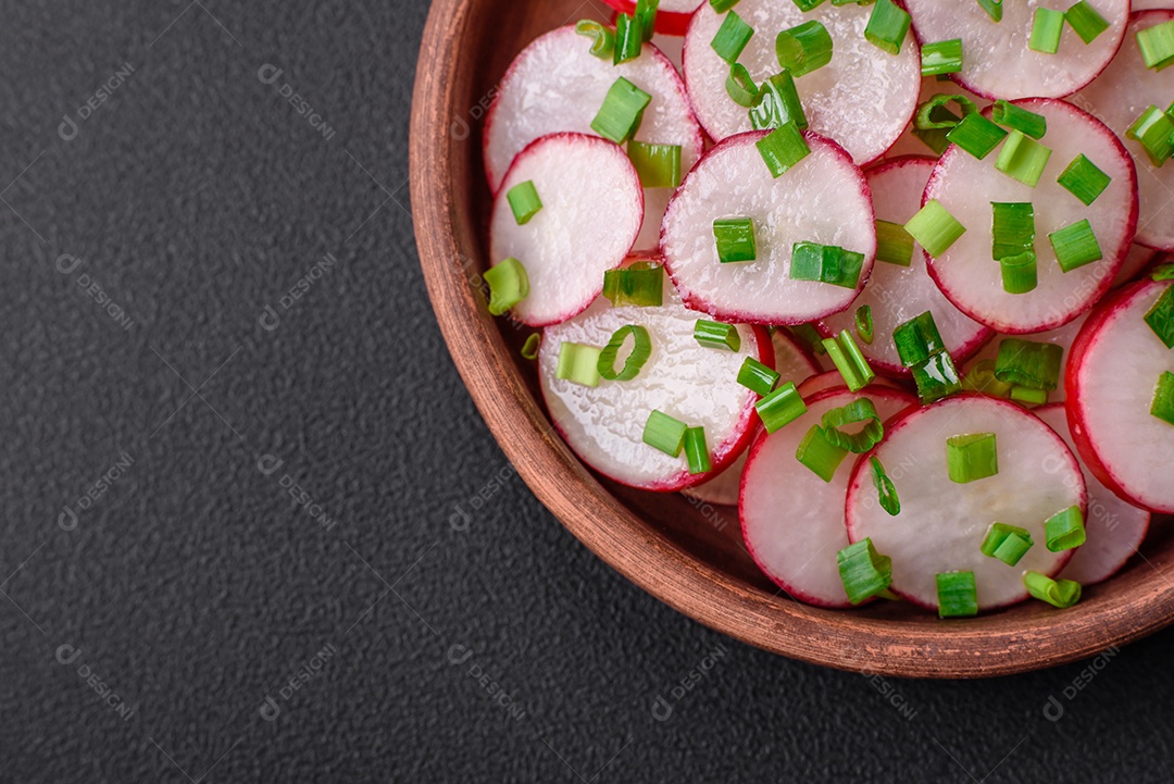 Deliciosa salada fresca de rabanetes fatiados com cebolinha, sal e azeite sobre um fundo escuro de concreto