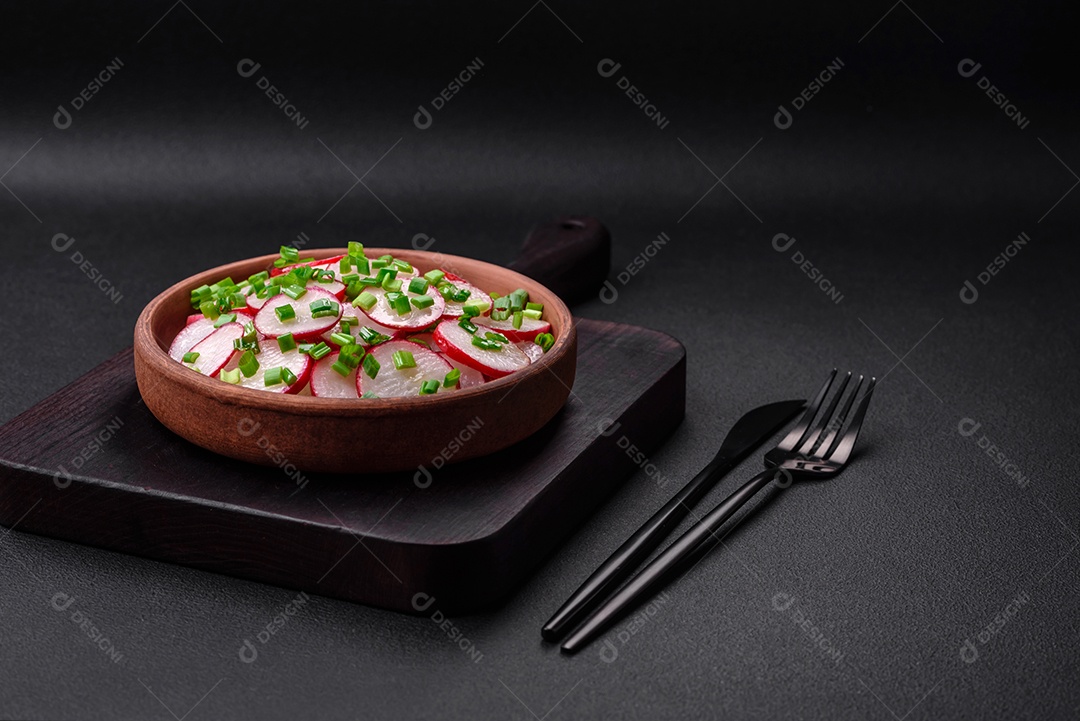 Deliciosa salada fresca de rabanetes fatiados com cebolinha, sal e azeite sobre um fundo escuro de concreto