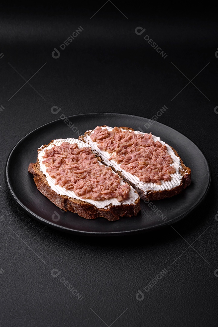 Deliciosos sanduíches compostos por torradas grelhadas, atum enlatado e cream cheese sobre um fundo escuro de concreto