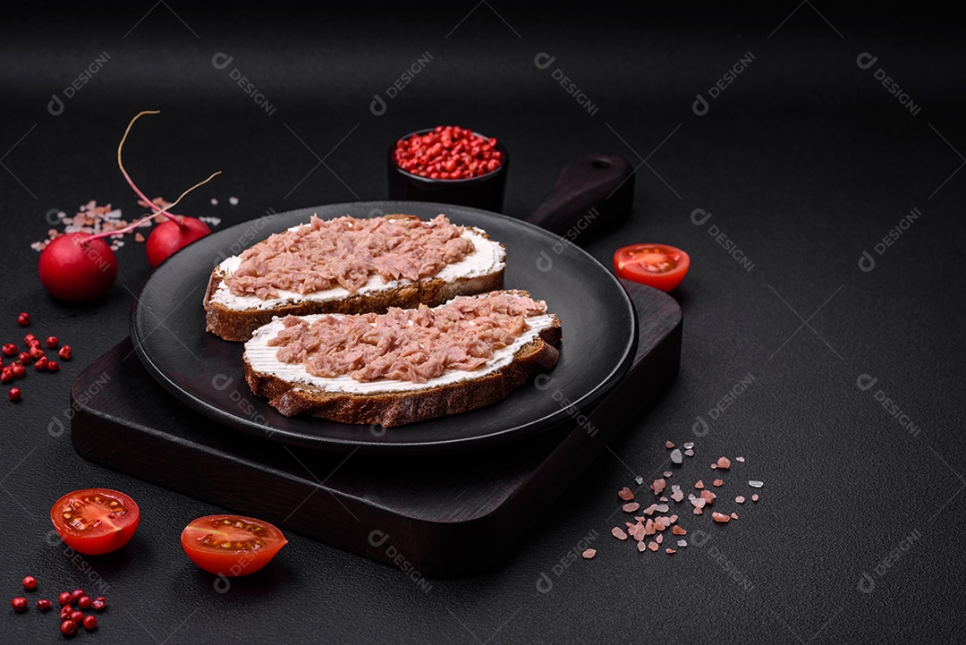 Deliciosos sanduíches compostos por torradas grelhadas, atum enlatado e cream cheese sobre um fundo escuro de concreto