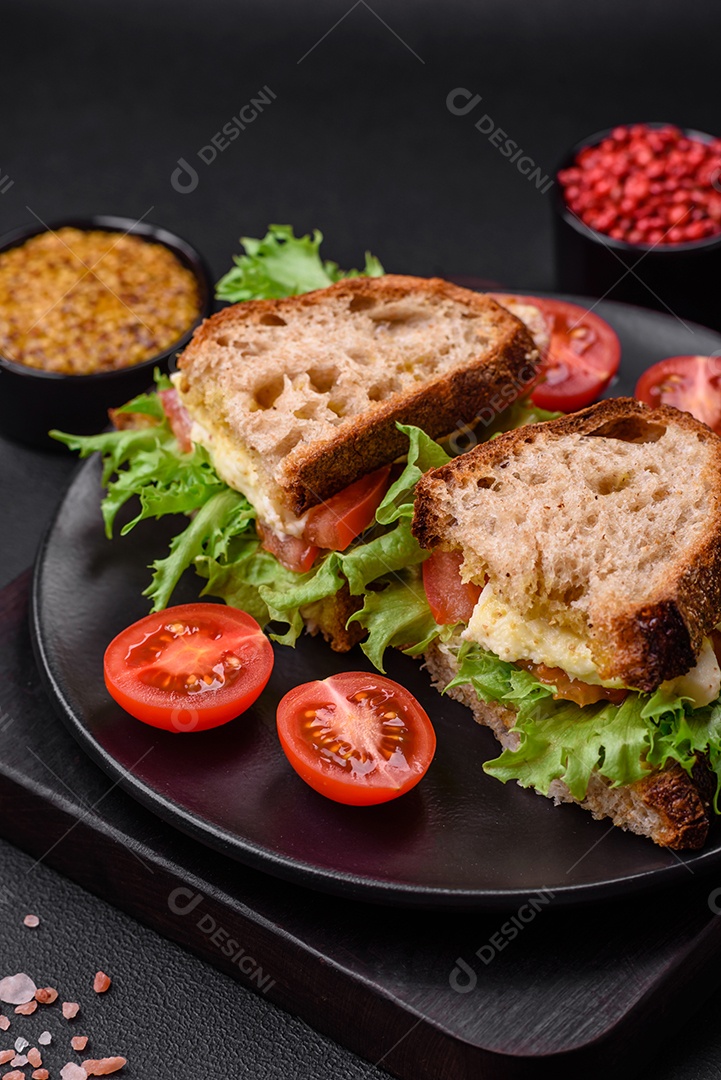Delicioso sanduíche caprese com torradas grelhadas, mussarela, alface e tomate sobre fundo escuro de concreto