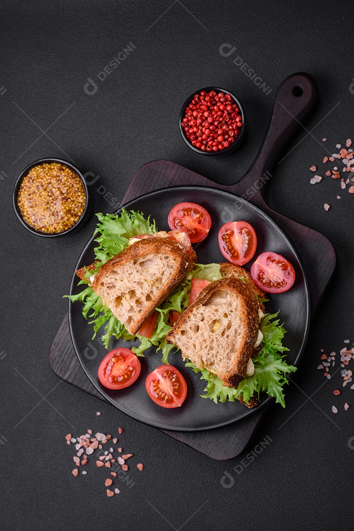 Delicioso sanduíche caprese com torradas grelhadas, mussarela, alface e tomate sobre fundo escuro de concreto