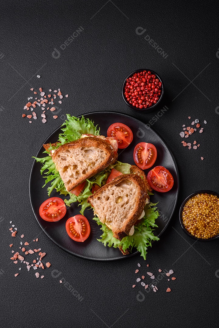 Delicioso sanduíche caprese com torradas grelhadas, mussarela, alface e tomate sobre fundo escuro de concreto