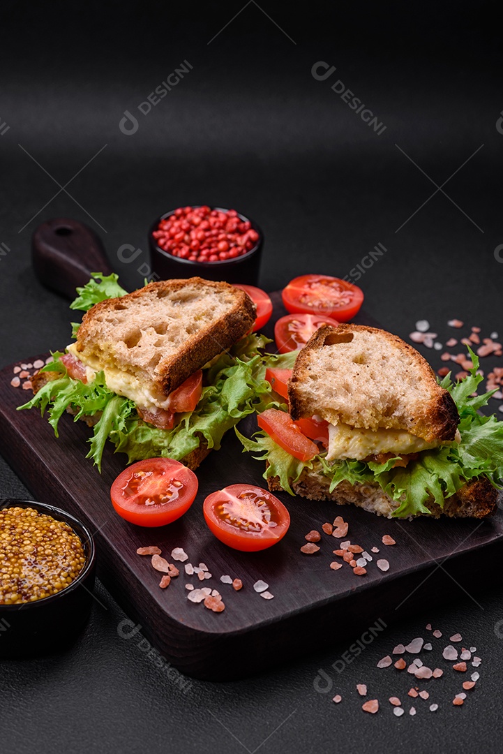 Delicioso sanduíche caprese com torradas grelhadas, mussarela, alface e tomate sobre fundo escuro de concreto