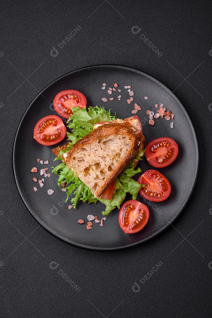 Delicioso sanduíche caprese com torradas grelhadas, mussarela, alface e tomate sobre fundo escuro de concreto