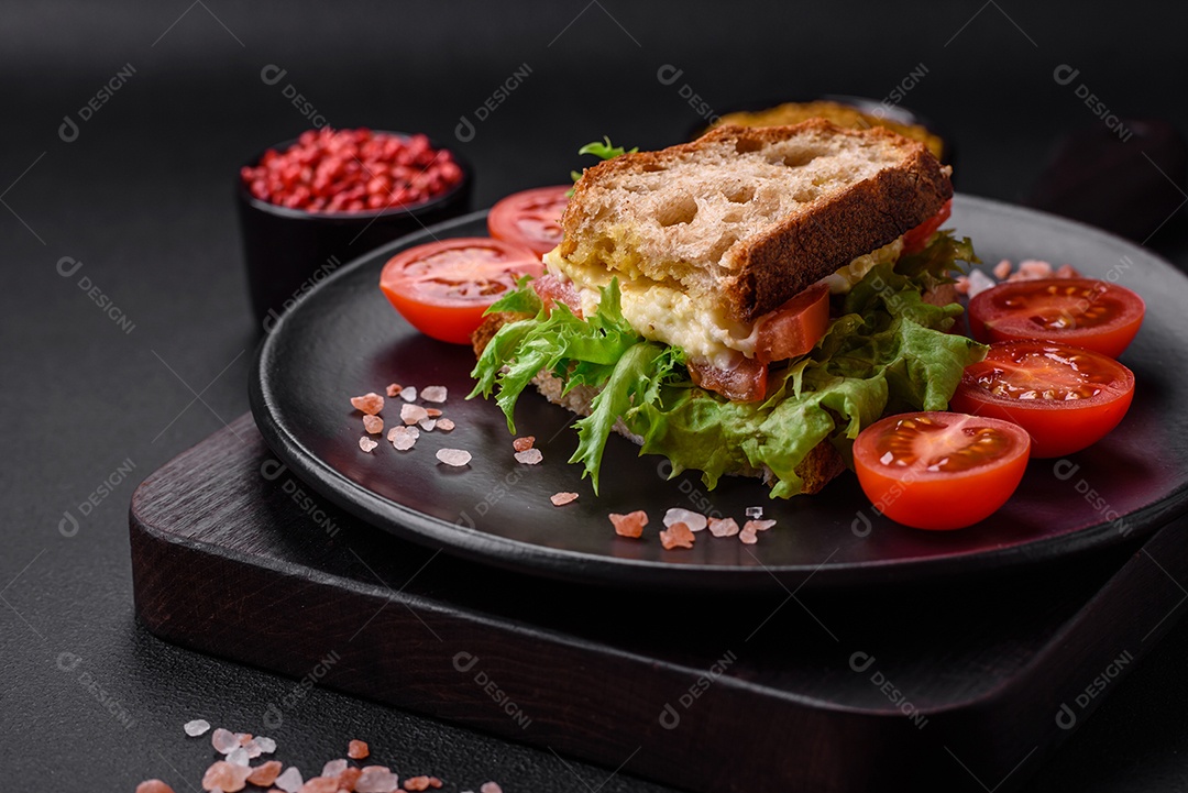 Delicioso sanduíche caprese com torradas grelhadas, mussarela, alface e tomate sobre fundo escuro de concreto
