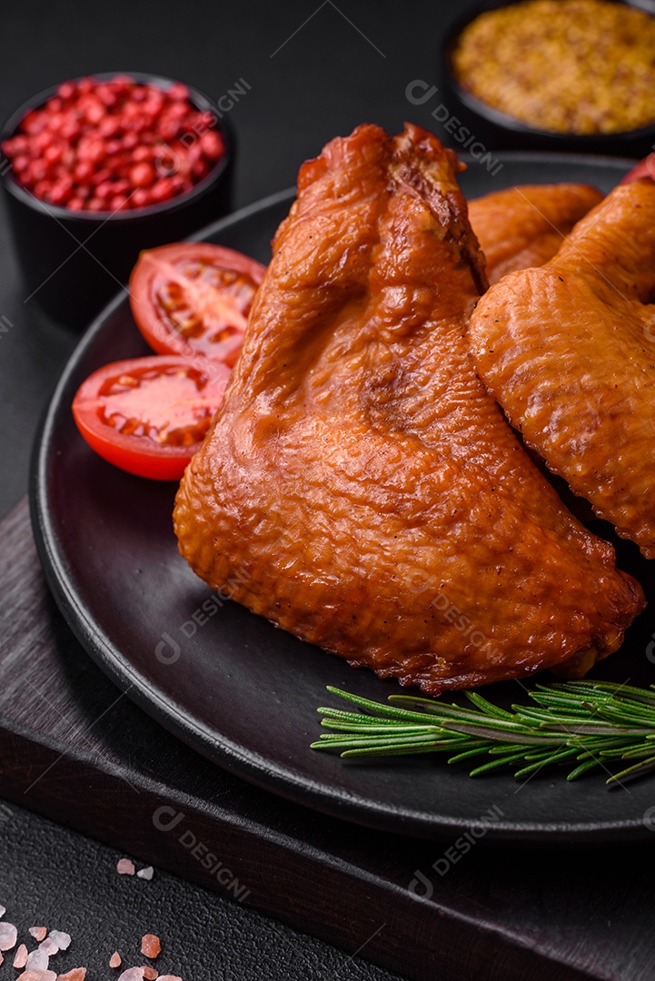 Deliciosas asas de frango grelhado com especiarias e ervas em um fundo escuro de concreto