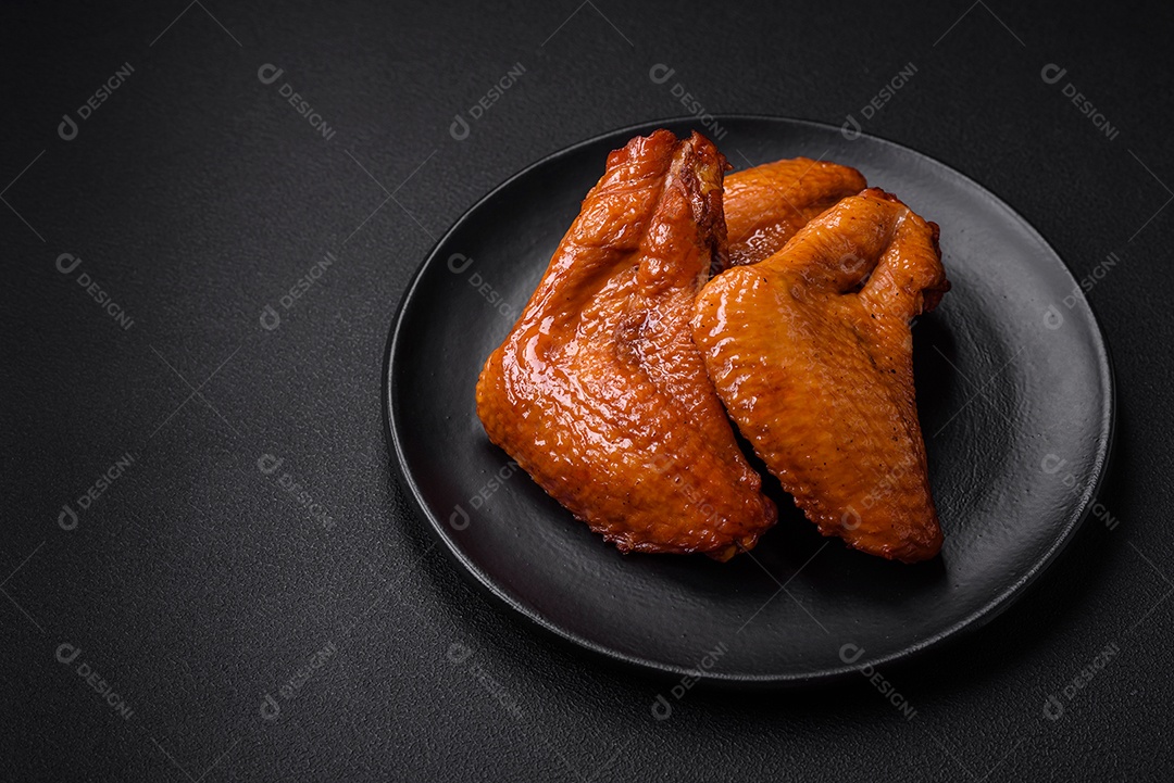 Deliciosas asas de frango grelhado com especiarias e ervas em um fundo escuro de concreto