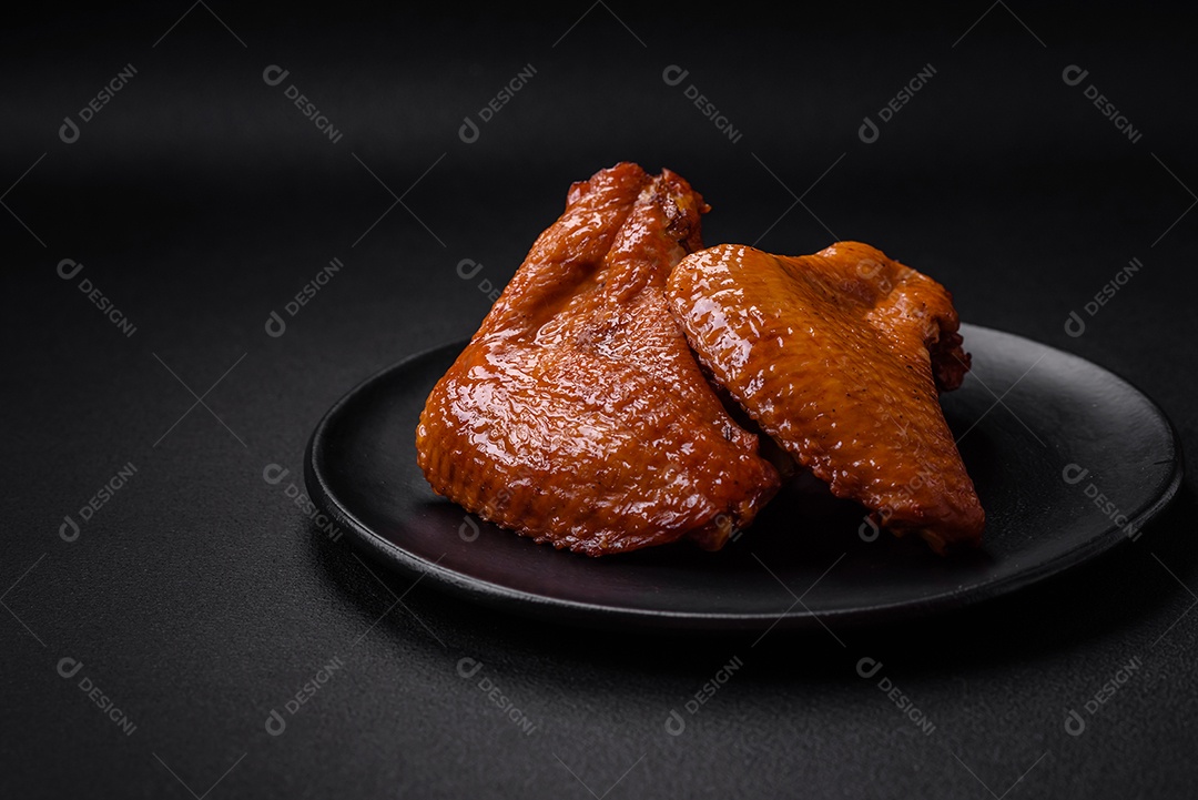 Deliciosas asas de frango grelhado com especiarias e ervas em um fundo escuro de concreto