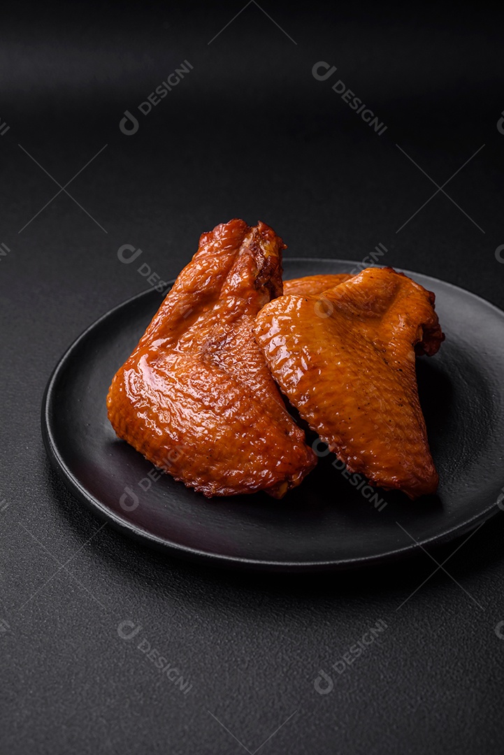 Deliciosas asas de frango grelhado com especiarias e ervas em um fundo escuro de concreto