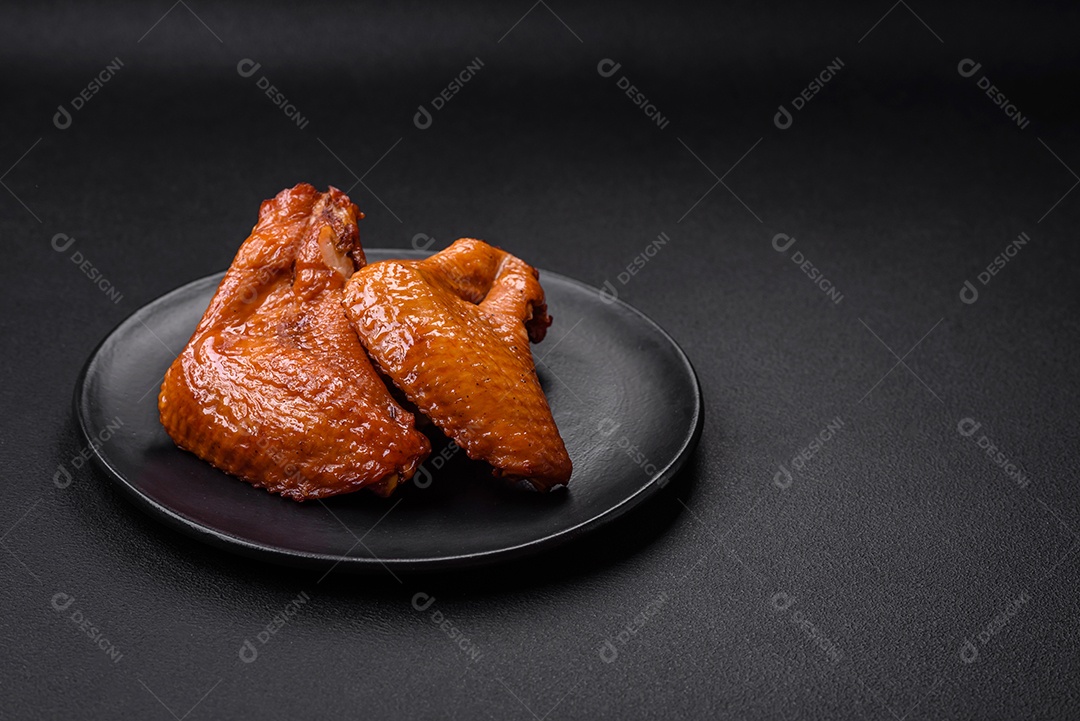 Deliciosas asas de frango grelhado com especiarias e ervas em um fundo escuro de concreto