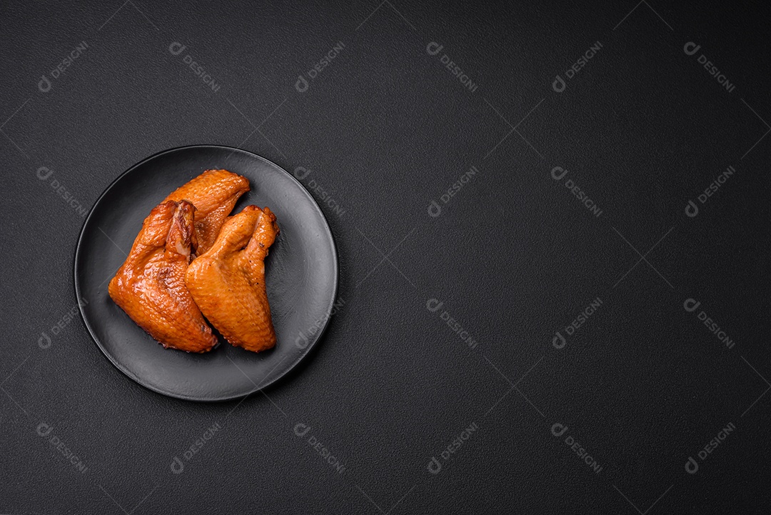 Deliciosas asas de frango grelhado com especiarias e ervas em um fundo escuro de concreto