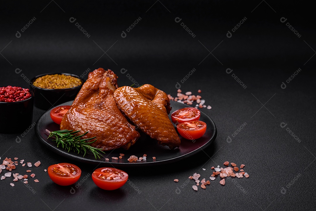 Deliciosas asas de frango grelhado com especiarias e ervas em um fundo escuro de concreto