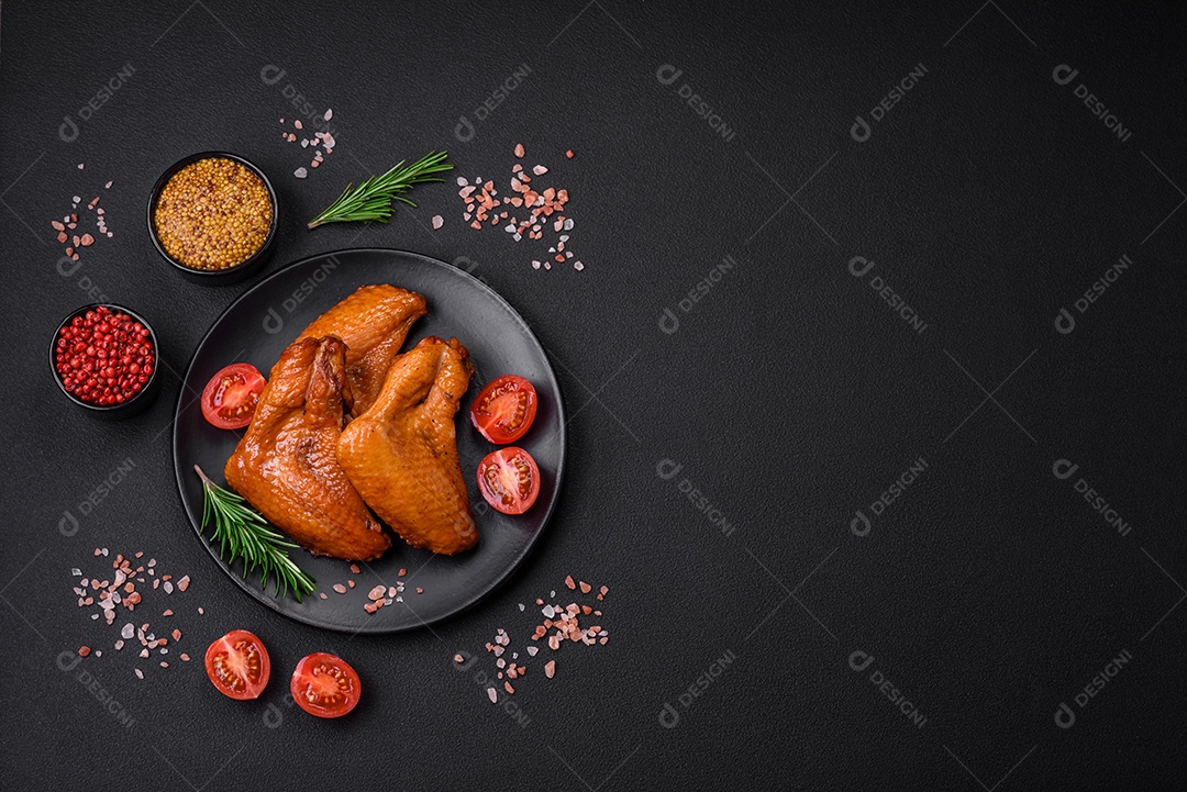 Deliciosas asas de frango grelhado com especiarias e ervas em um fundo escuro de concreto