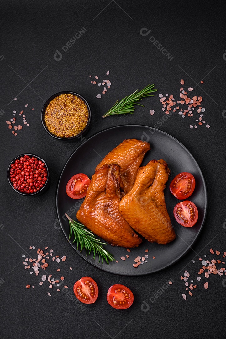 Deliciosas asas de frango grelhado com especiarias e ervas em um fundo escuro de concreto