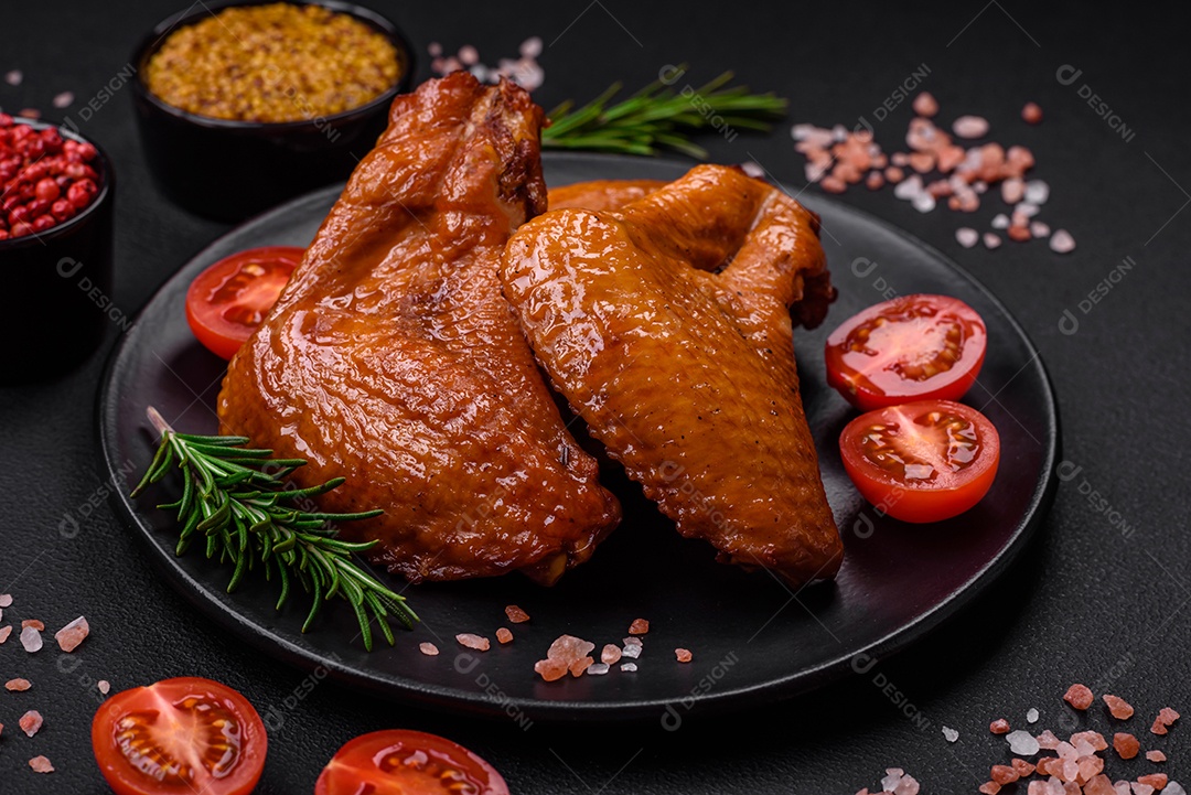 Deliciosas asas de frango grelhado com especiarias e ervas em um fundo escuro de concreto