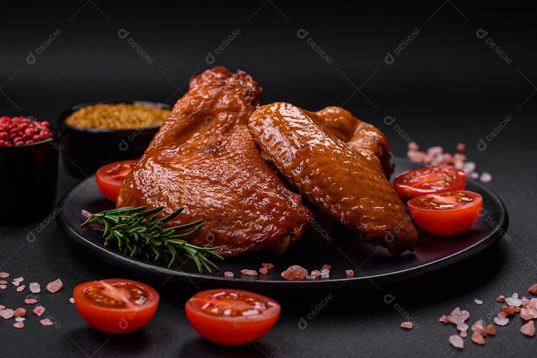 Deliciosas asas de frango grelhado com especiarias e ervas em um fundo escuro de concreto