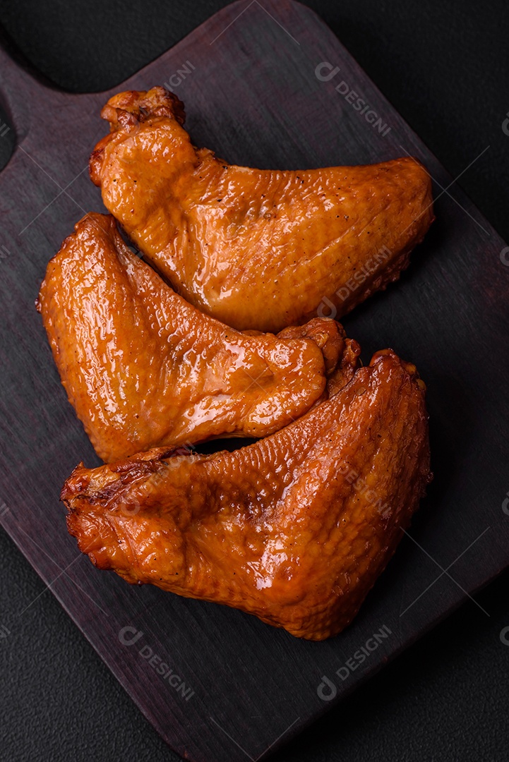 Deliciosas asas de frango grelhado com especiarias e ervas em um fundo escuro de concreto